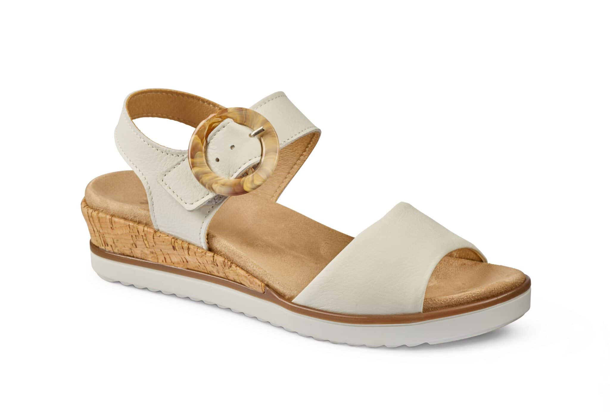 Vit sandal med kilklack och rund bältesdetalj, bekväm och stilren design.