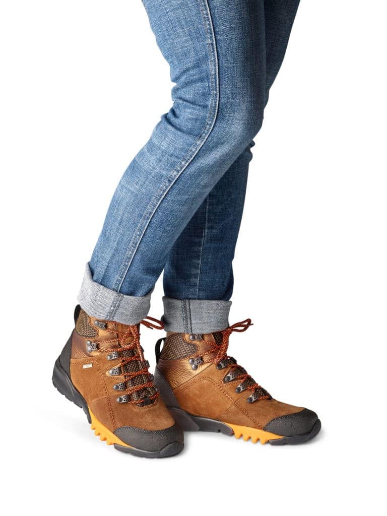 Person som bär bruna vandringskängor och jeans.
