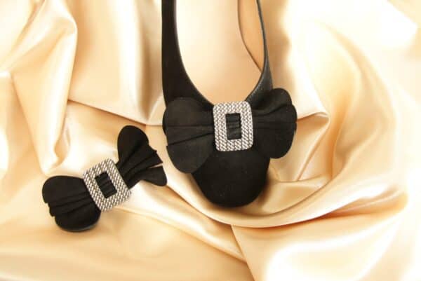 Läderväska och hårspänne med diamantdetaljer på sammetsbakgrund.