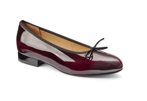 Ballerinaskor i vinröd lackläder med liten klack och rosettdetalj.
