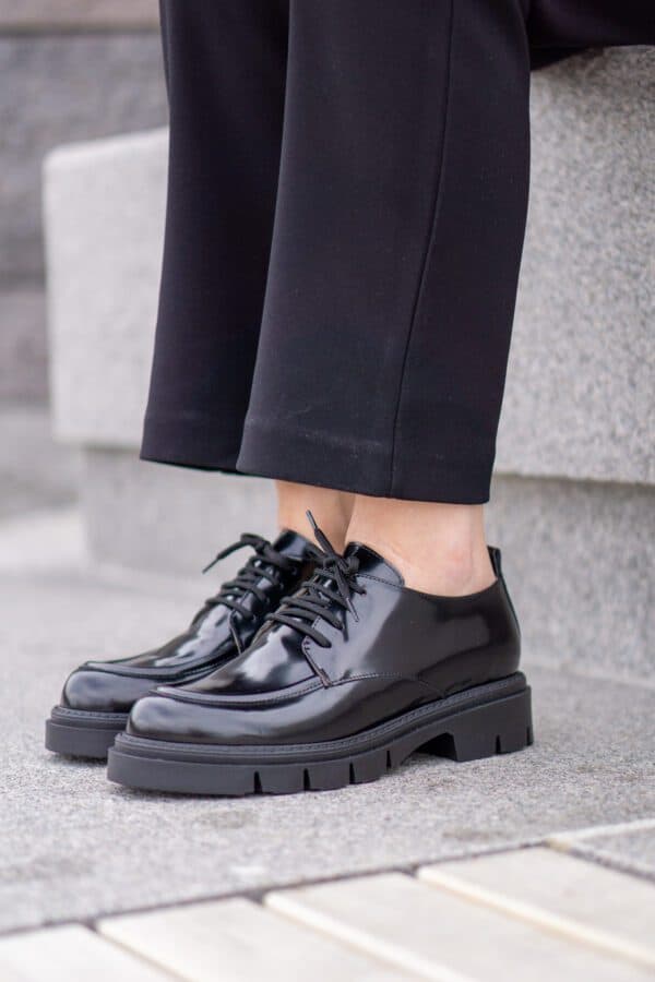 Svart lackskor med tjock sula och snörning, perfekt för vardagsbruk.
